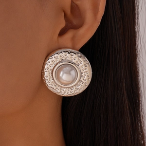 Detail of vintage round hammered silver earring with centered pearl on model