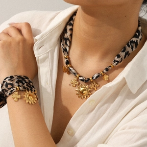 Leopard print ribbon necklace and bracelet set with gold sun and cross pendants on a model