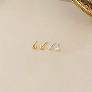 Close-up of minimalist gold and silver heart stud earrings in 925 sterling silver