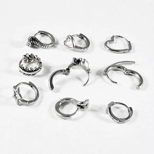 Close-up of vintage silver hoop earrings featuring heart, snake, and skull punk designs