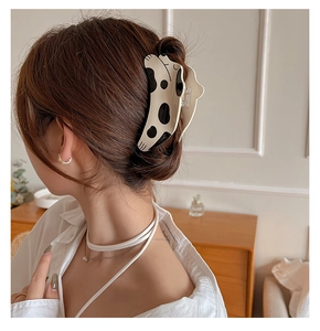 Detail view of a large cow print acetate hair claw clip worn on a woman's hair