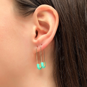 Golden safety pin earrings with mint green enamel detail worn on a model's ear