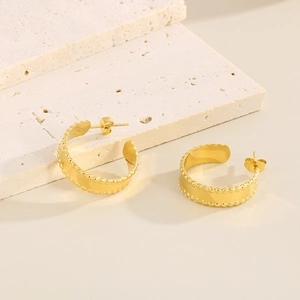 Detailed macro view of 18k gold-plated C-shaped earrings with fine beaded texture edges