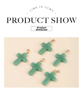 Detail of five light green cross pendants with gold bail hooks on a beige surface