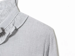 Detail shot of grey and white striped top featuring a ruffled collar and cotton-linen texture