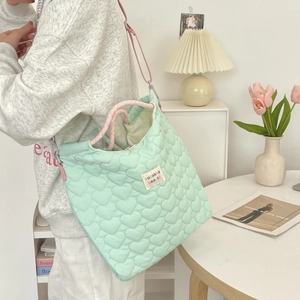 Detail van mintgroene gewatteerde hartjes-tote bag met roze gevlochten handvat en schouderriem