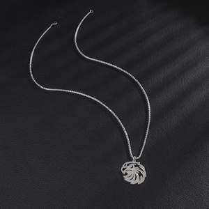 Polished stainless steel eagle head pendant necklace on a black textured background