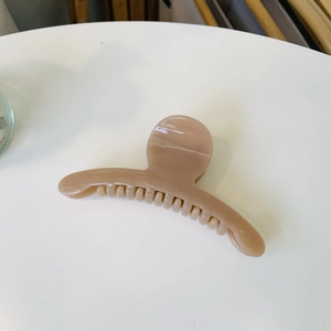 Detail of a medium milk tea brown hair claw clip made of glossy resin in top view