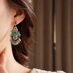 Detail of luxury crystal drop fringe earrings with blue and grey gemstones on model