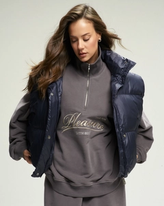 Detail of grey half-zip sweatshirt with navy puffer vest and chest embroidery