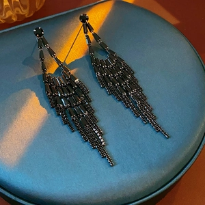 Detail of long black fringe tassel earrings with bead accents on a jewelry tray