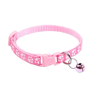 Detail of pink pet collar featuring white paw prints, safety buckle and a shiny bell