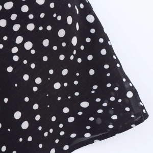 Close-up of lightweight black chiffon fabric with white polka dots and delicate texture