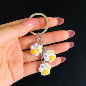 Macro detail of cute white resin cat paw keychains with yellow and purple paw pads