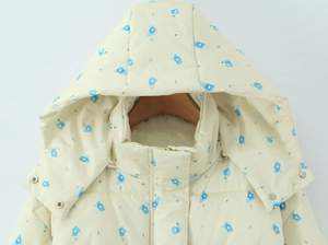Close-up detail of floral puffer jacket featuring blue flower print and hood with metal snaps