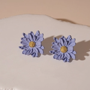 Close-up of matte purple floral earrings with golden center on white stone stand