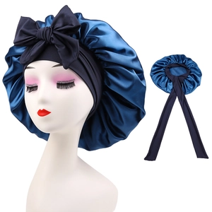 Detail view of navy blue satin sleeping cap featuring large decorative bow and long ribbons