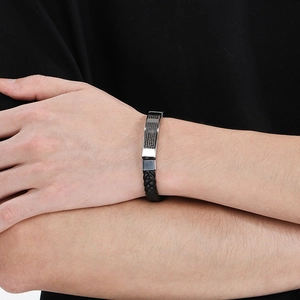 Close-up of woven black leather bracelet with silver Lord's Prayer engraved plate