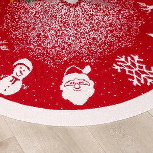 Jupe de sapin de Noël en tricot rouge avec motifs Père Noël sur parquet en bois clair