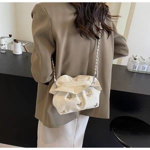 Detailed view of white pleated cloud bag with silver butterfly and metal chain strap