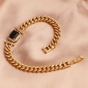 Macro view of gold-plated Cuban chain bracelet with rectangular black gemstone and zircon pavé