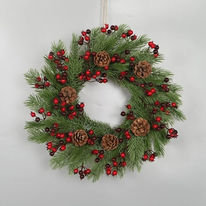 Christmas wreath with green pine needles, red berries, and natural pine cones for decor