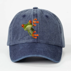 Detailed macro view of embroidered red-eyed tree frog on navy washed denim baseball cap