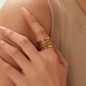Close-up of four-piece gold stackable rings featuring smooth, hammered and Cuban link textures