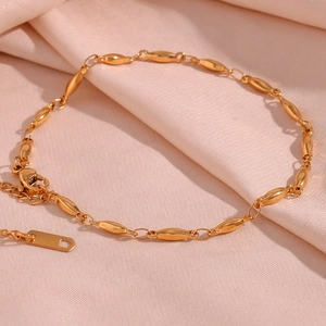 Macro shot of 18K gold plated stainless steel olive bead chain on pink silk fabric