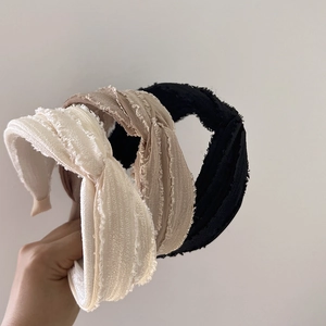 Detailed view of three-piece knotted headbands in black, grey, and cream woven fabric