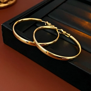 Vue détaillée de grandes créoles dorées sur un support à bijoux noir élégant