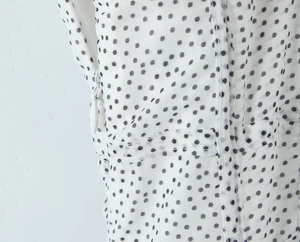 Detail shot of the invisible side zipper on a white and black polka dot chiffon dress