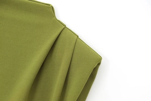 Detailed close-up of olive green dress fabric showing ruched texture and padded shoulder