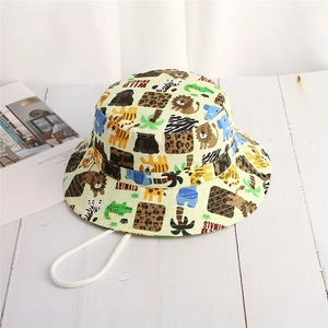 Pale yellow kids bucket hat with wild animal prints and windproof rope on wood background