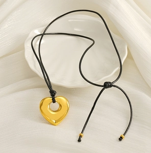 Detail of a polished gold hollow heart pendant on a black adjustable cord necklace