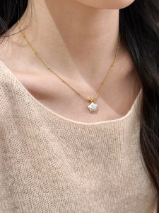 Gros plan d'un collier étoile doré avec pendentif en nacre sur une chaîne satellite