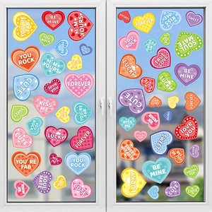 Colorful heart window clings with romantic phrases like BE MINE on glass surface