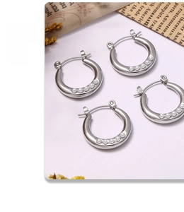 Detailed view of silver hoop earrings with white pearls on a purple aesthetic background