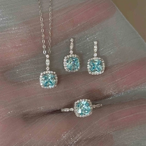 Macro view of aquamarine blue gemstone jewelry set with halo diamond necklace and ring