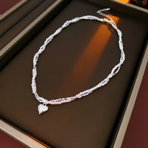 Detail of a double-layered pearl necklace with silver beads and a heart pendant