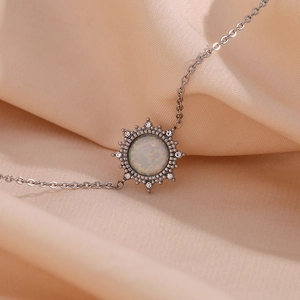 Macro shot of silver sun pendant bracelet with opal stone on silk fabric