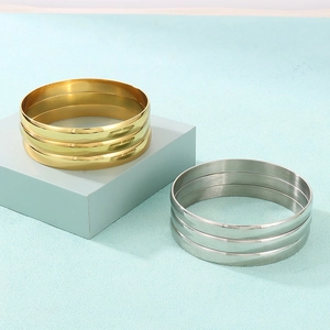 Polished gold and silver stainless steel minimalist nested bangle sets on blue blocks