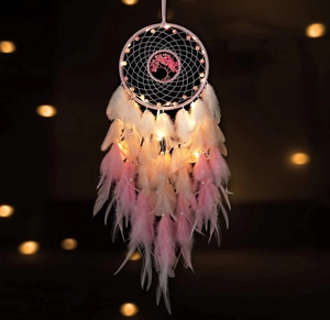 Detail of pink Tree of Life dream catcher with feathers and warm glowing LED lights