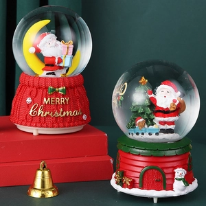 Close-up of two Christmas snow globes with Santa Claus and festive red bases