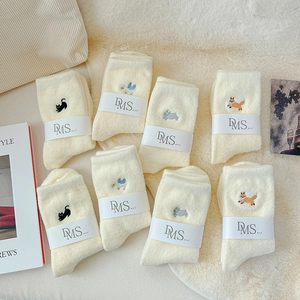 Detailed view of cream-colored fuzzy socks with cute animal embroidery on warm plush fabric