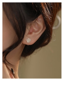 Detail view of a model wearing the small silver rose stud earring with clear metallic texture