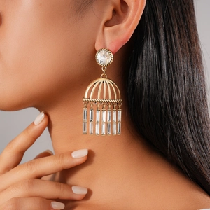 Detail view of retro gold hollow earrings with crystal tassels on a model's ear