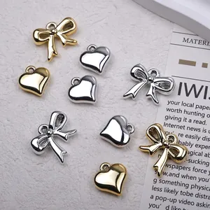 Polished gold and silver heart and bow pendants for DIY jewelry making on white background