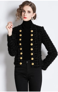 Close-up of black tweed jacket featuring gold embossed buttons and fringe texture
