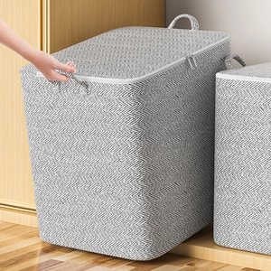 Detail of grey herringbone laundry basket with lid and handles next to a wooden closet